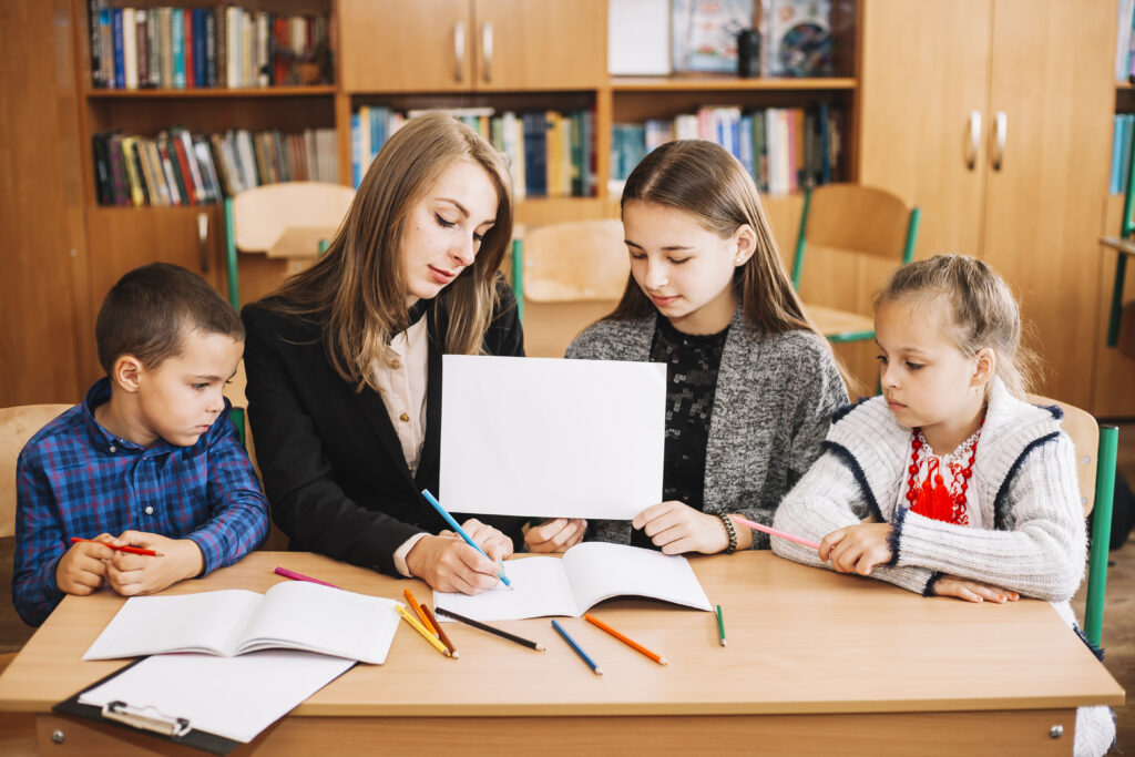 school-teacher-working-with-pupils-desk